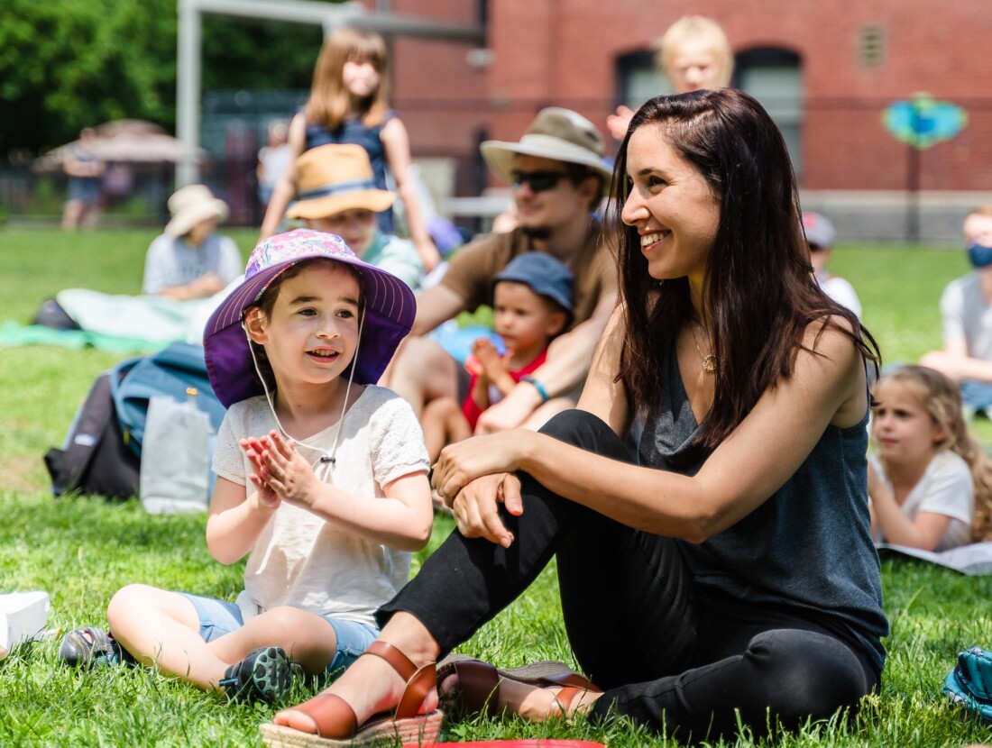 A woman and a child sitting on grass.