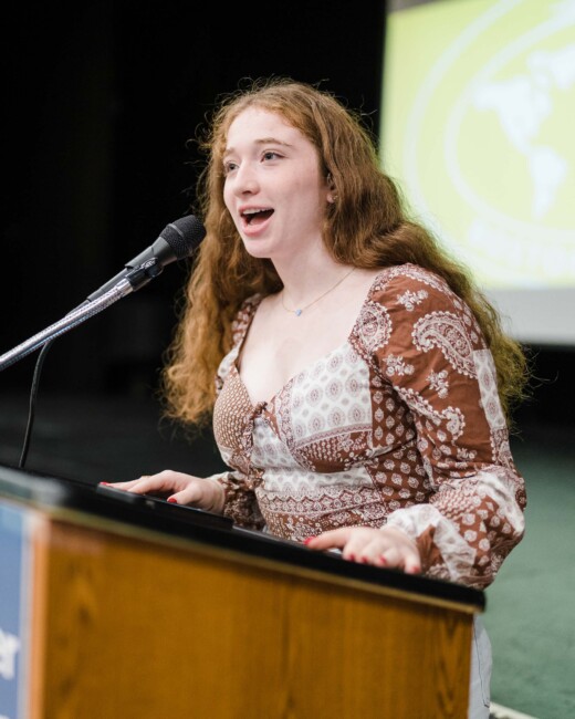 A teenager speaking at a podium.