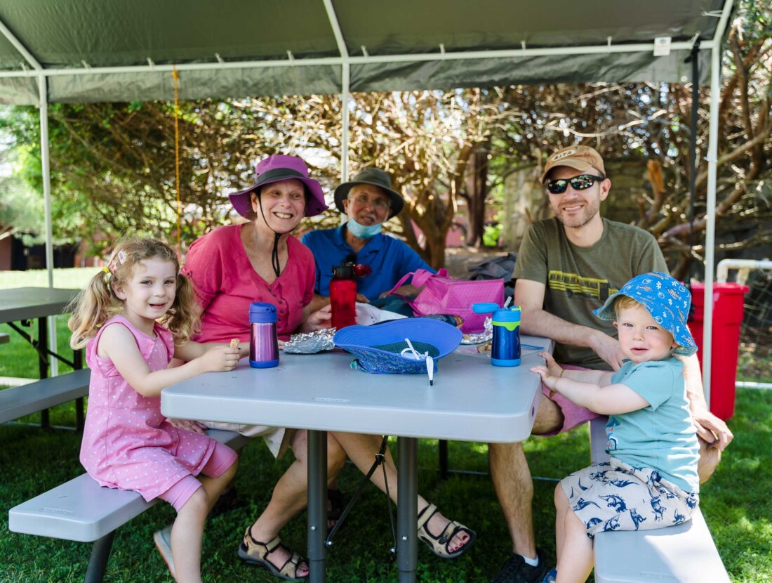 A family sitting on a picnic table together.