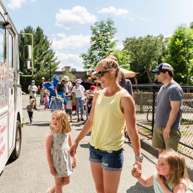 A mother and her two children in front of an ice cream truck.