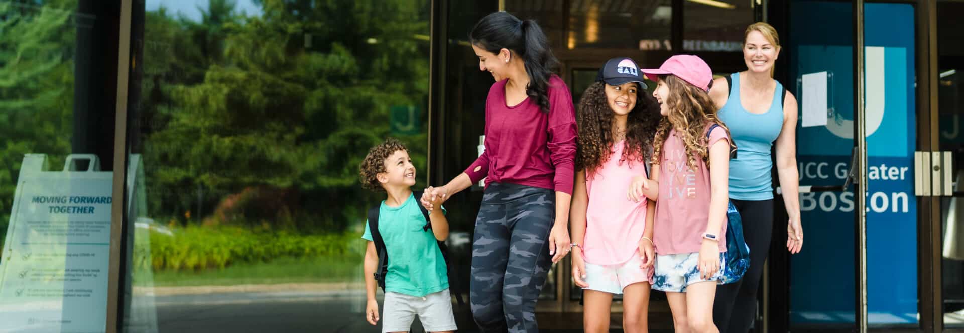 Two women and three kids walking out of JCC Greater Boston.