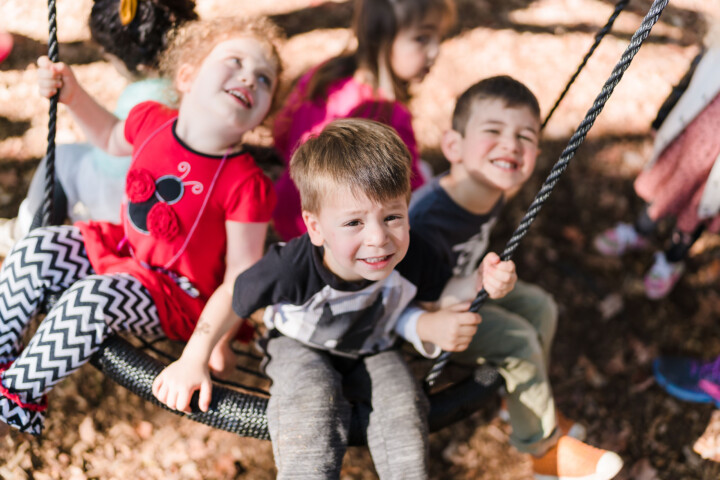 Kids on swing in outdoor playground.