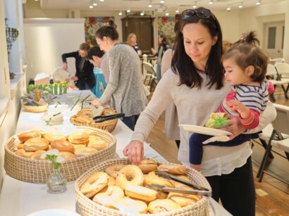 A mother and her child at a buffet table with bagels.