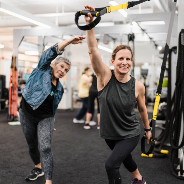 A woman working out in a fitness center with a personal trainer.