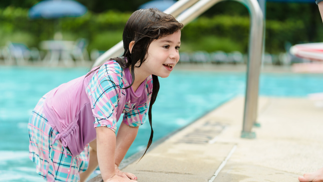 A young girl at an outdoor pool.