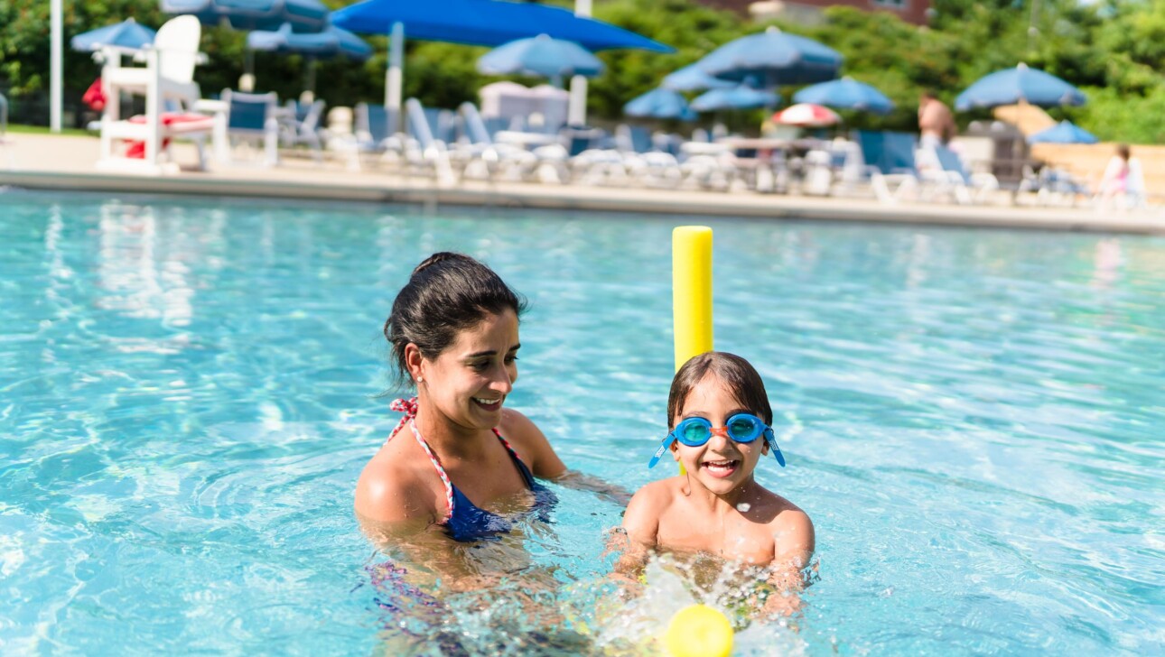 A child and their mother in an outdoor pool.