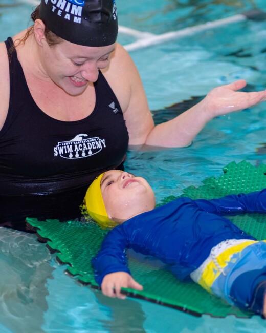 A swim instructor teaching a young student.
