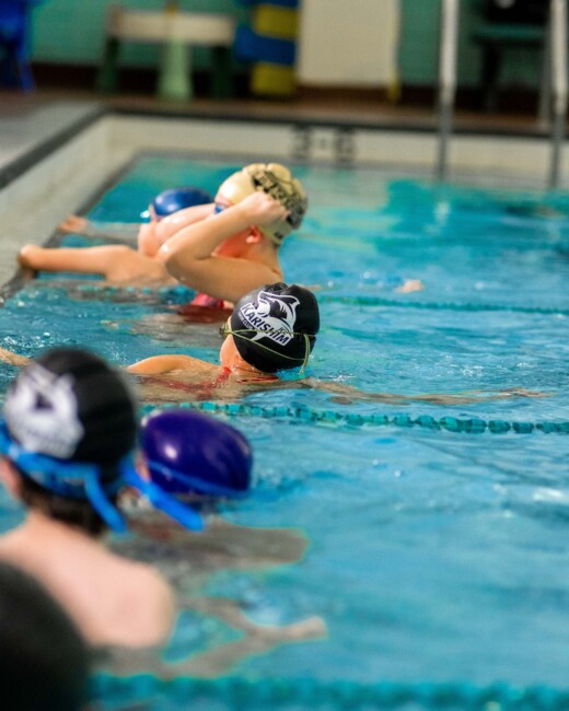 A swim team at the edge of a pool.