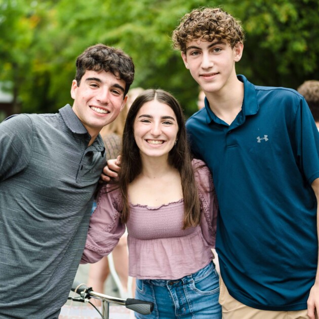 Three teenagers smiling.