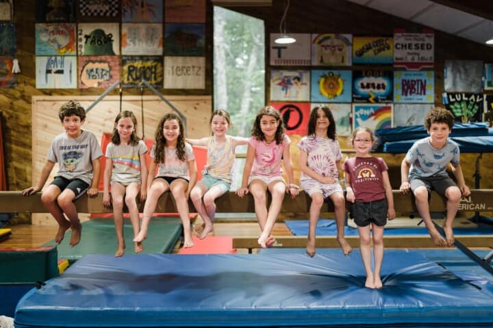 Kids smiling on a balance beam at Camp Grossman.