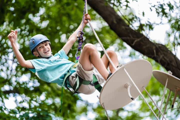Boy climbing to the top of a ropes course.