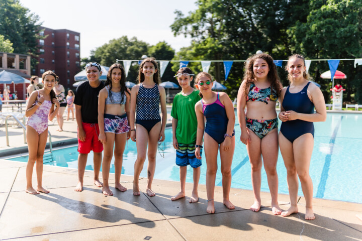 Group of girls smiling outside a pool.