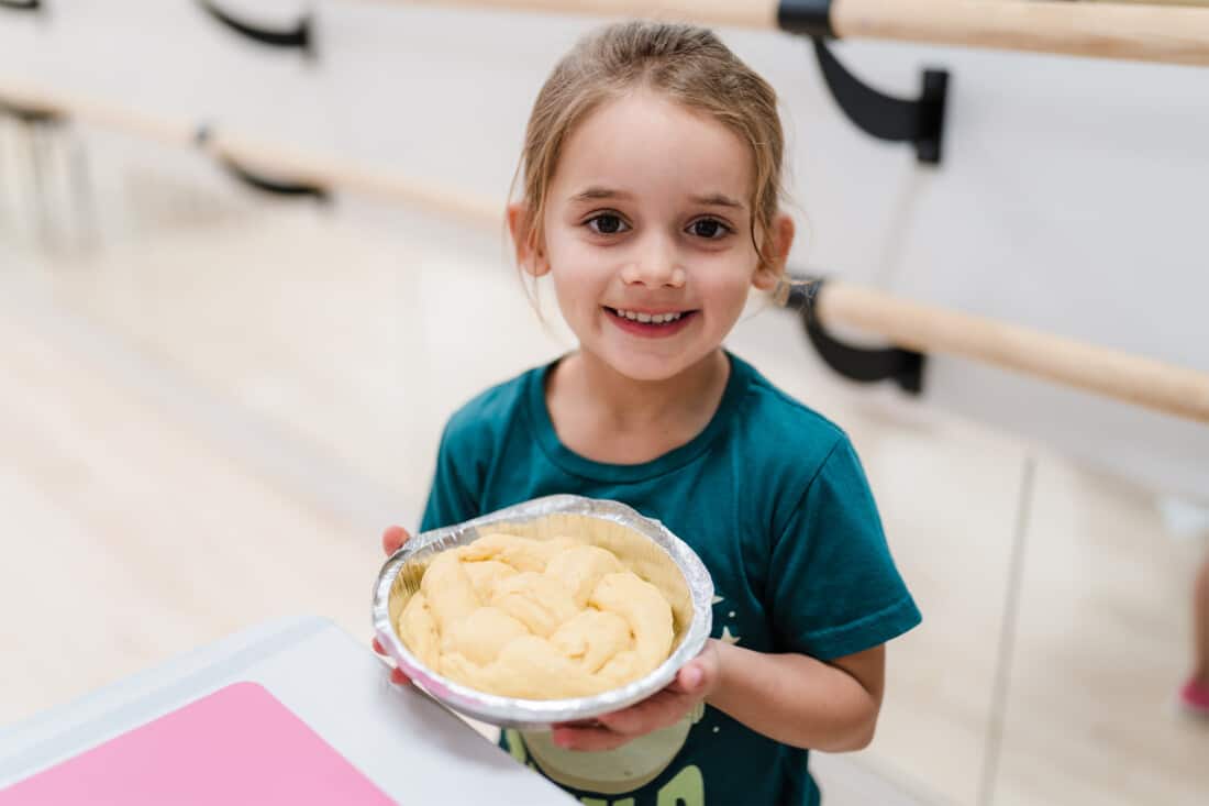 Girl holding a braided round challah.