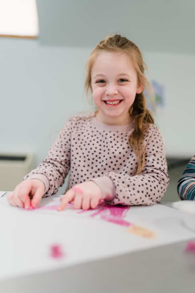 Girl smiling while doing a craft.