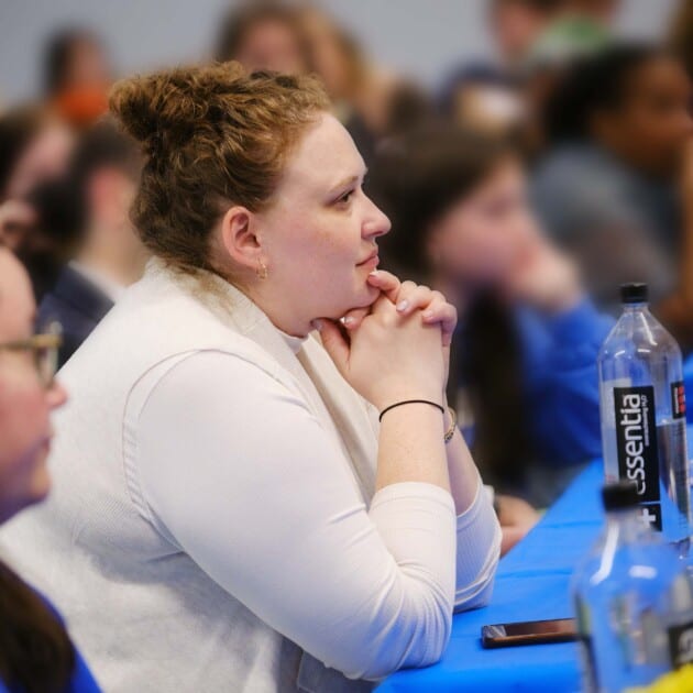 A woman listening to a lecture.