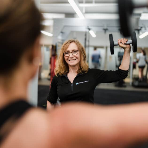 Personal trainer showing a client how to lift a weight.