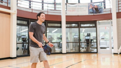 A man playing pickleball in the gym.