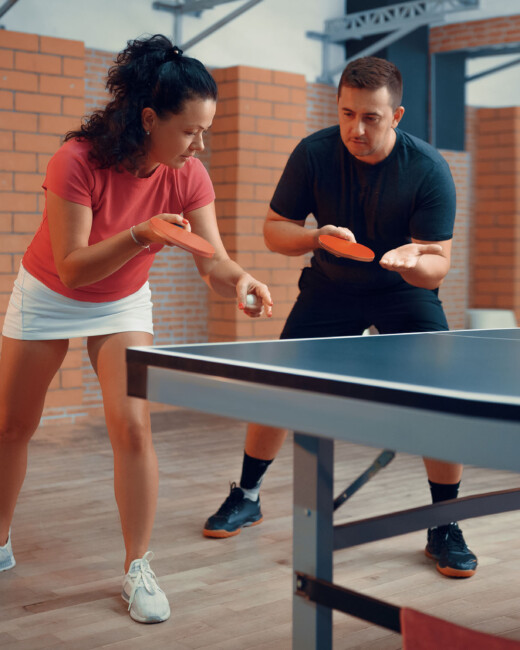 A coach teaching someone how to play table tennis.