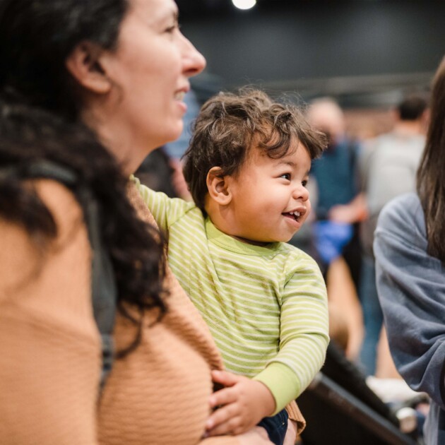 Mom holding her young child at an event.