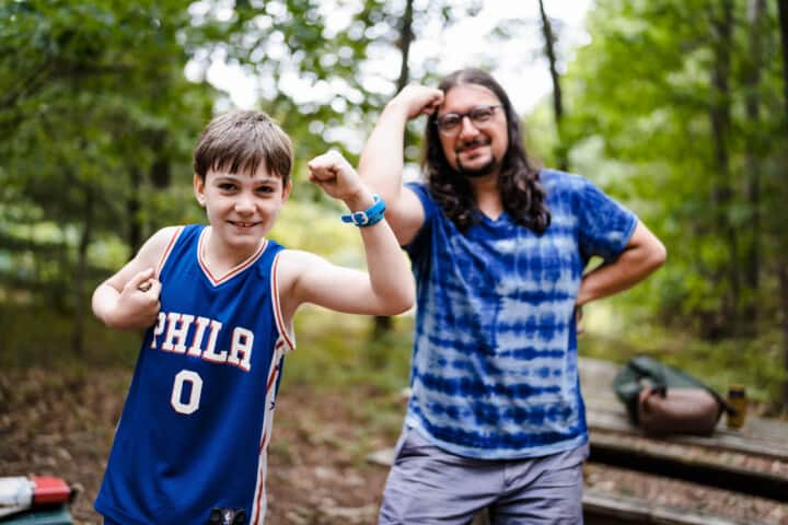 Boy flexing his biceps with a staff member at Camp Grossman.
