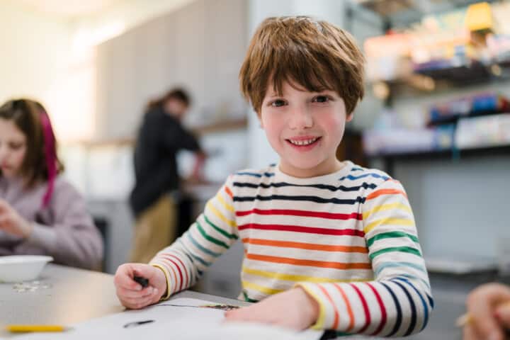 Boy smiling while doing a craft.