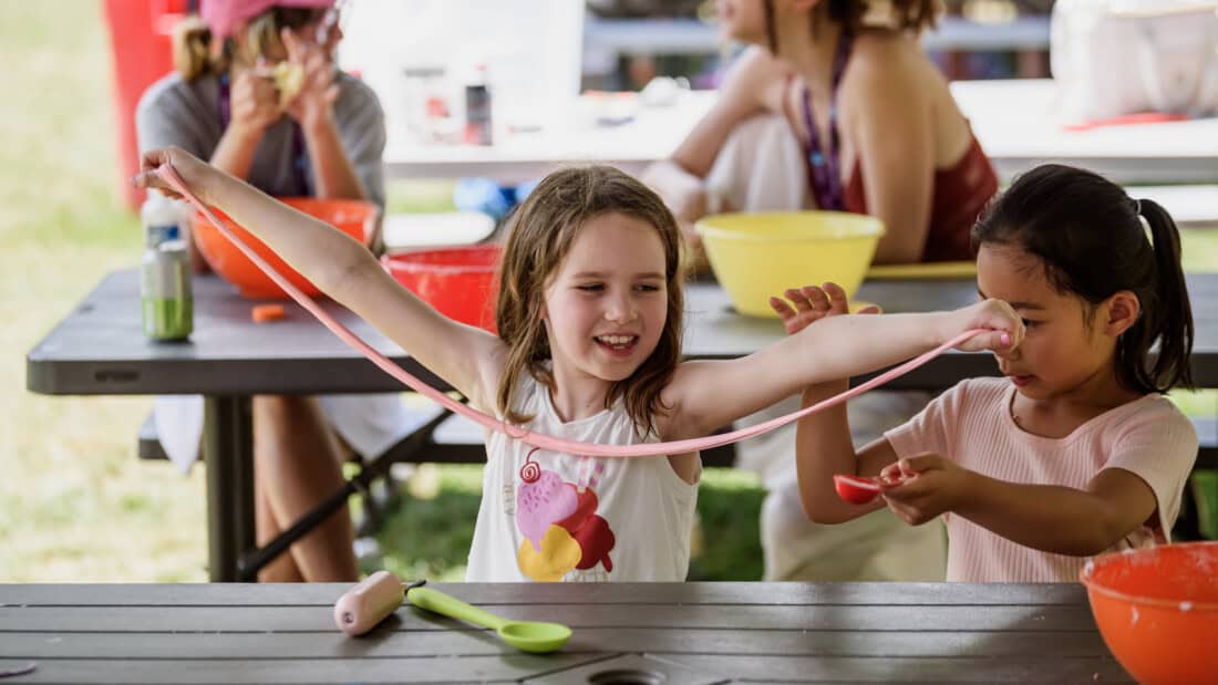 Girl playing with slime outdoors at camp.