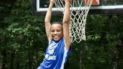 Boy on a basketball hoop.