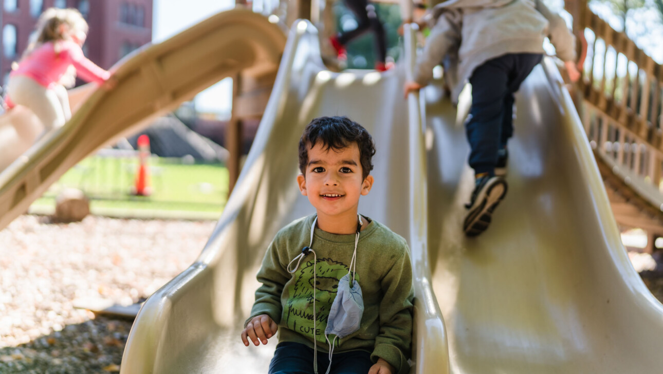 A young boy at the bottom of a slide.
