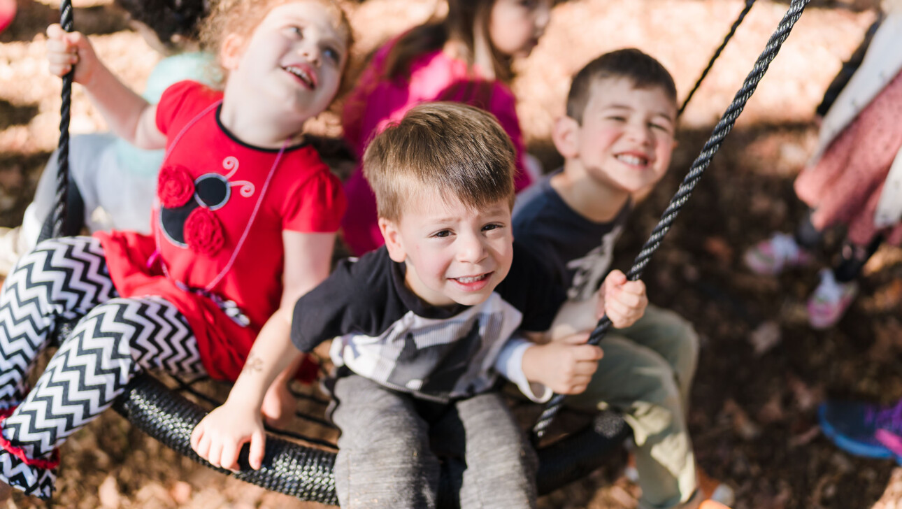 Kids on swing in outdoor playground.