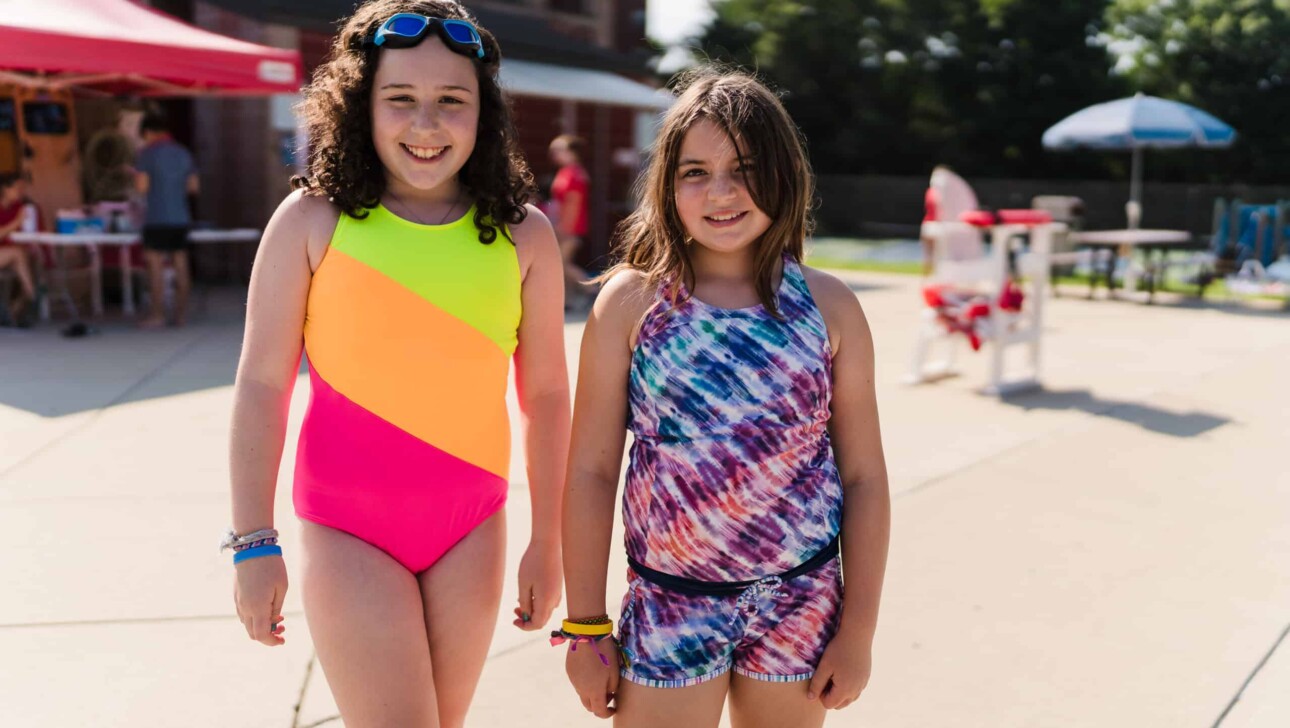 Girls smiling outside a pool.