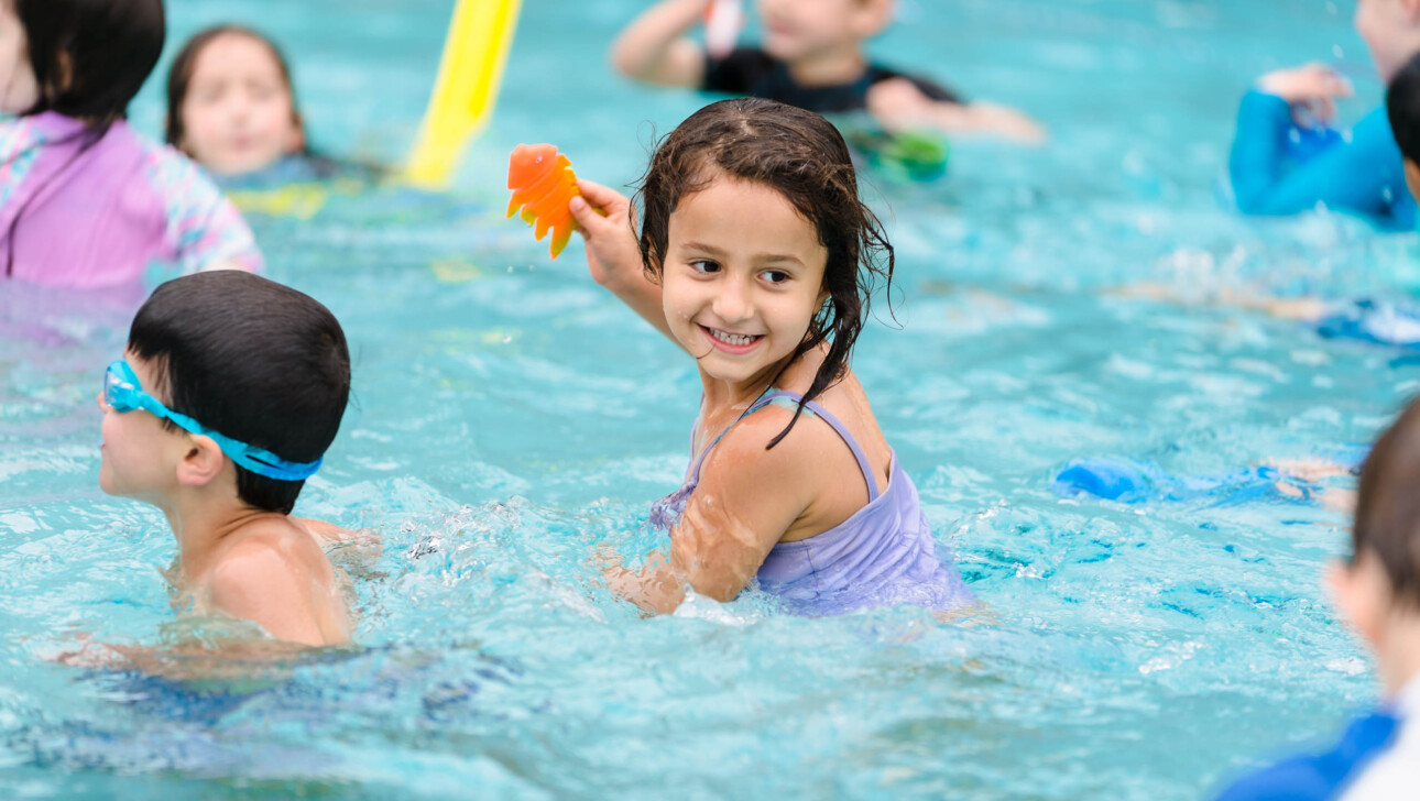 A young girl playing in a pool.