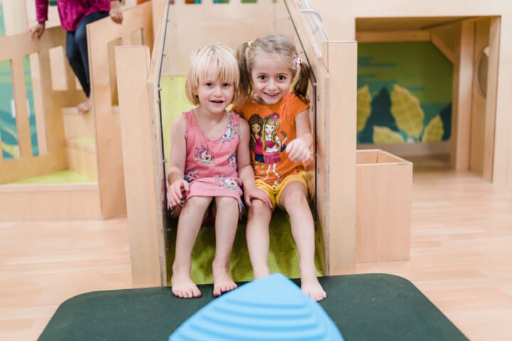 Two girls sitting and the edge of a slide.