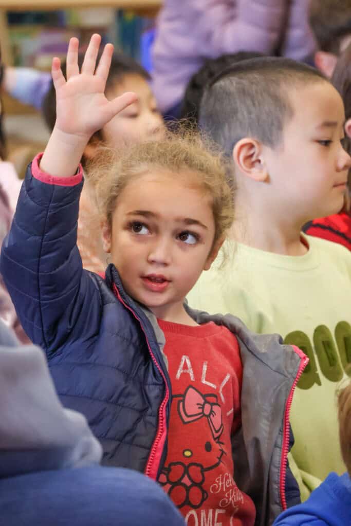 Girl raising her hand in Discovery Club.