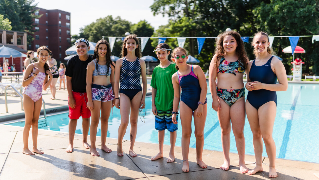 Group of girls smiling outside a pool.