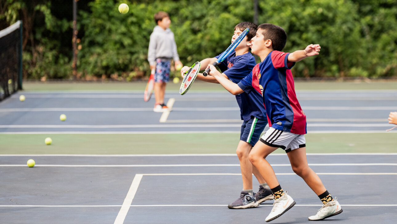 Boys going for a ball at Tennis Camp.