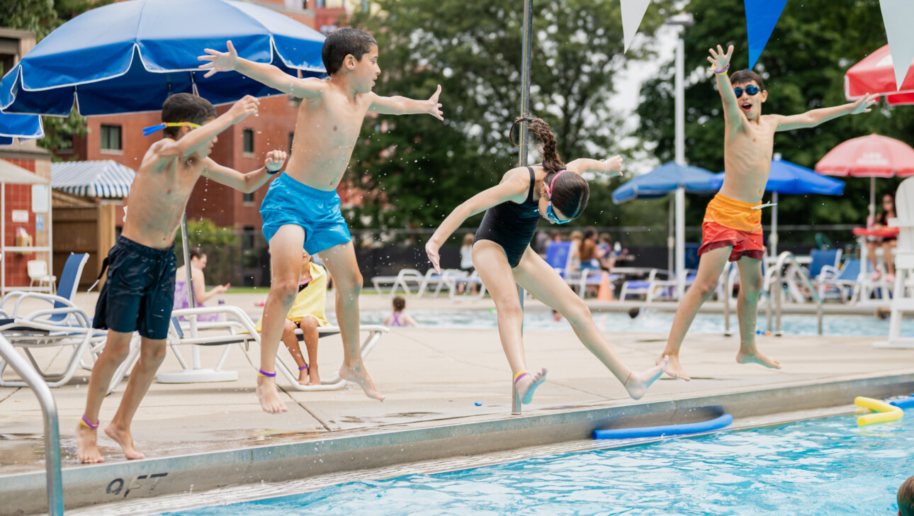Kids jumping into the outdoor pool.