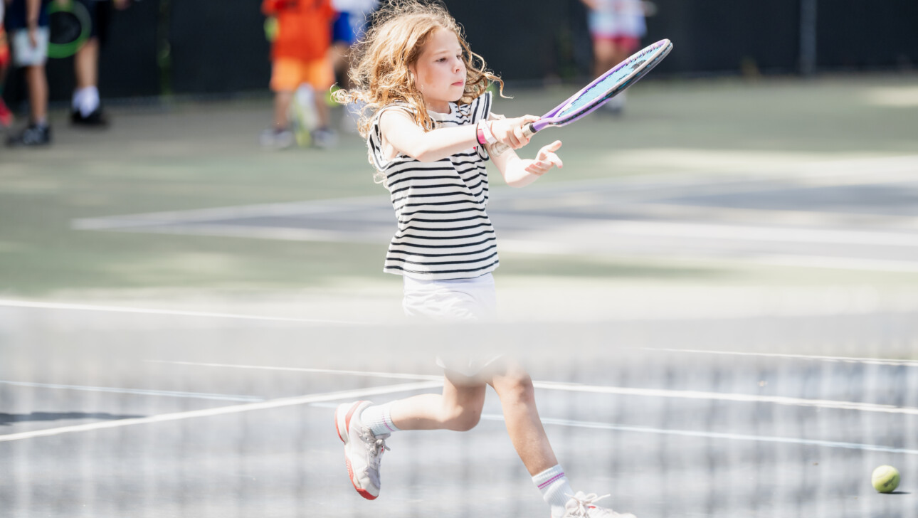 Girl swinging a racket at Tennis Camp.