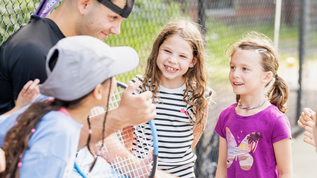 Girls chatting with a Tennis Camp counselor.