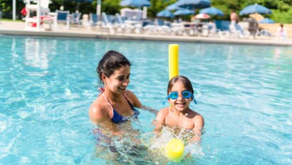 Boy and his mom playing in the outdoor pool.