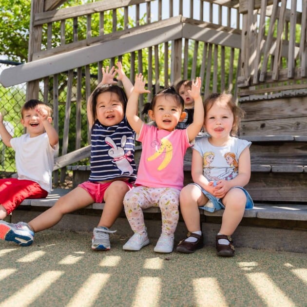 Kids outdoors with their hands in the air.