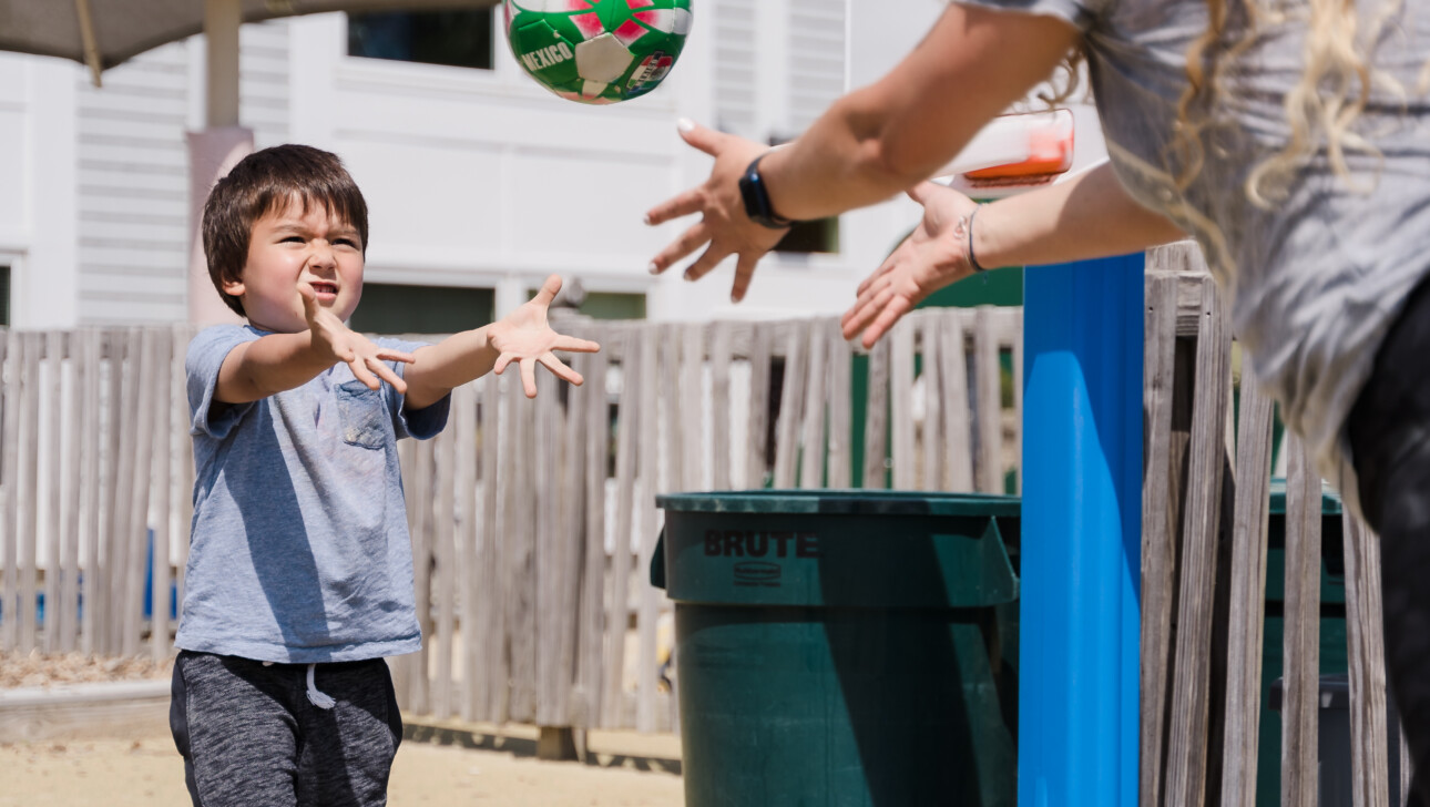 Boy playing catch with a teacher.