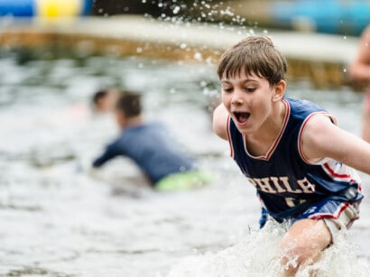 Boy running into the water at Camp Grossman.