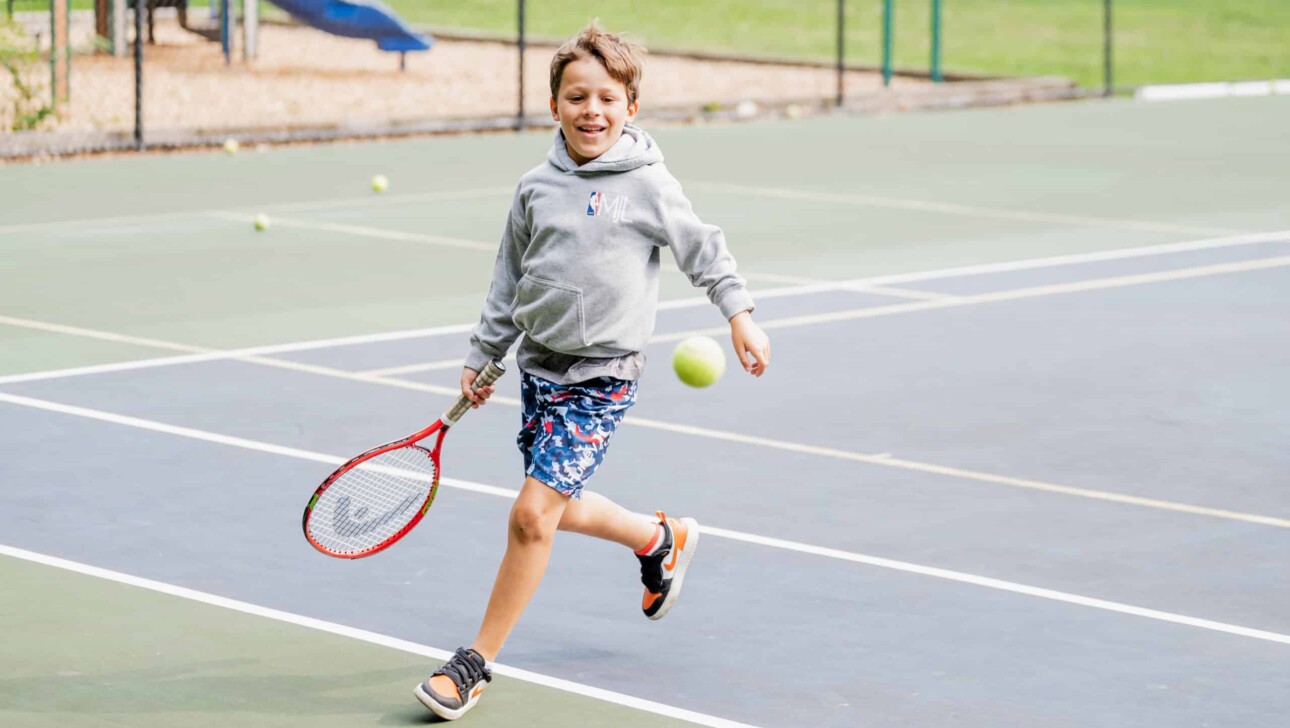 Kid playing tennis at camp.