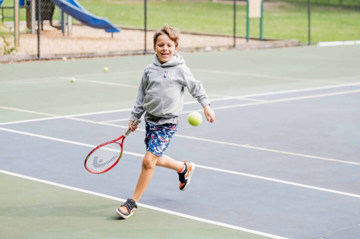Kid playing tennis at camp.