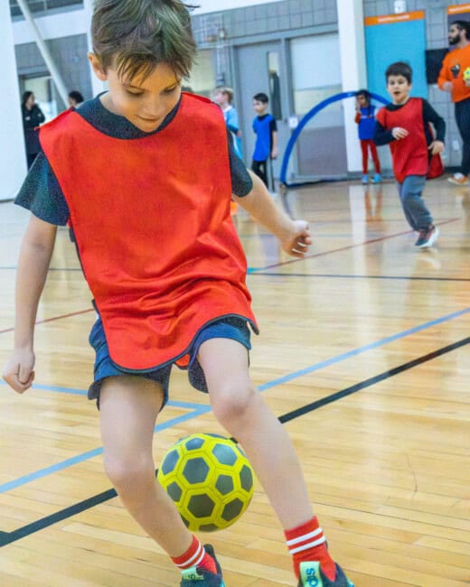 Kid playing soccer indoors.